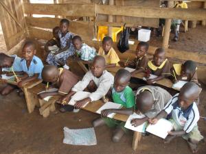 The children sat on the mud ground and used the benches as desks